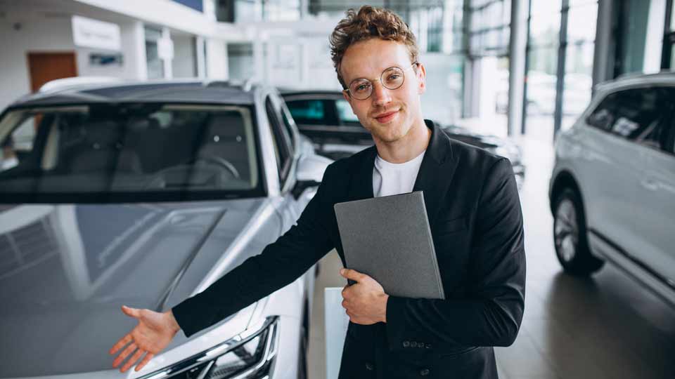 Ein Verkäufer zeigt auf ein Auto und erklärt dem Kunden die Konditionen beim Auto verkaufen Mainz
